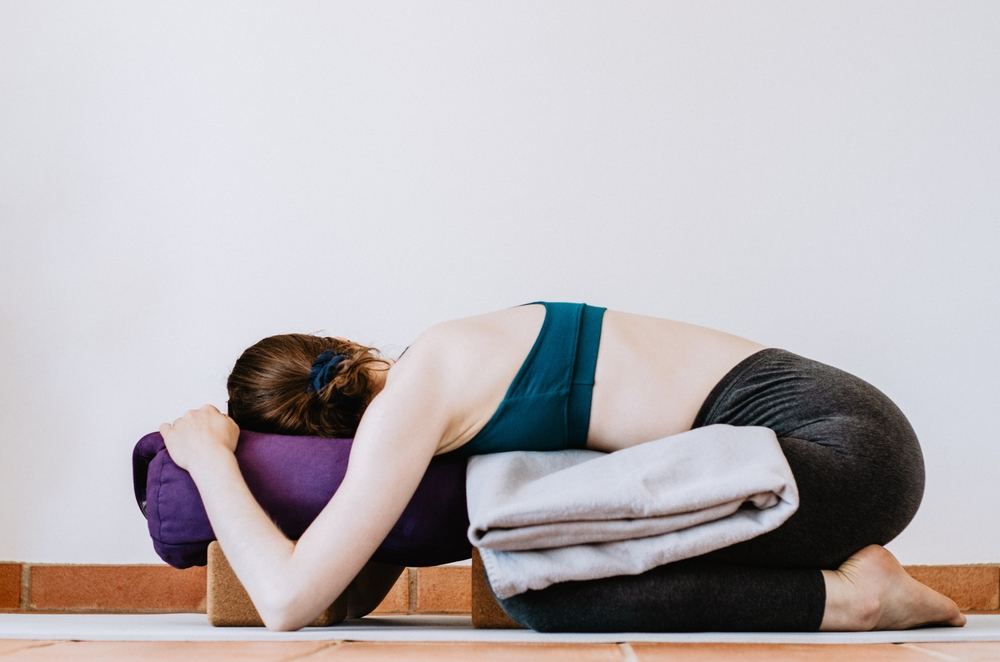 yoga practitioner in a restorative yoga pose yoga practitioner in a restorative yoga pose