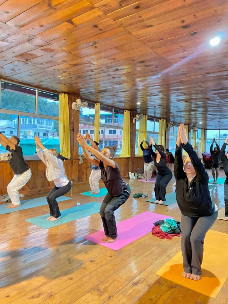 Yoga students practicing chair pose during yoga teacher training at Rishikul Yogshala Yoga students practicing chair pose during yoga teacher training at Rishikul Yogshala