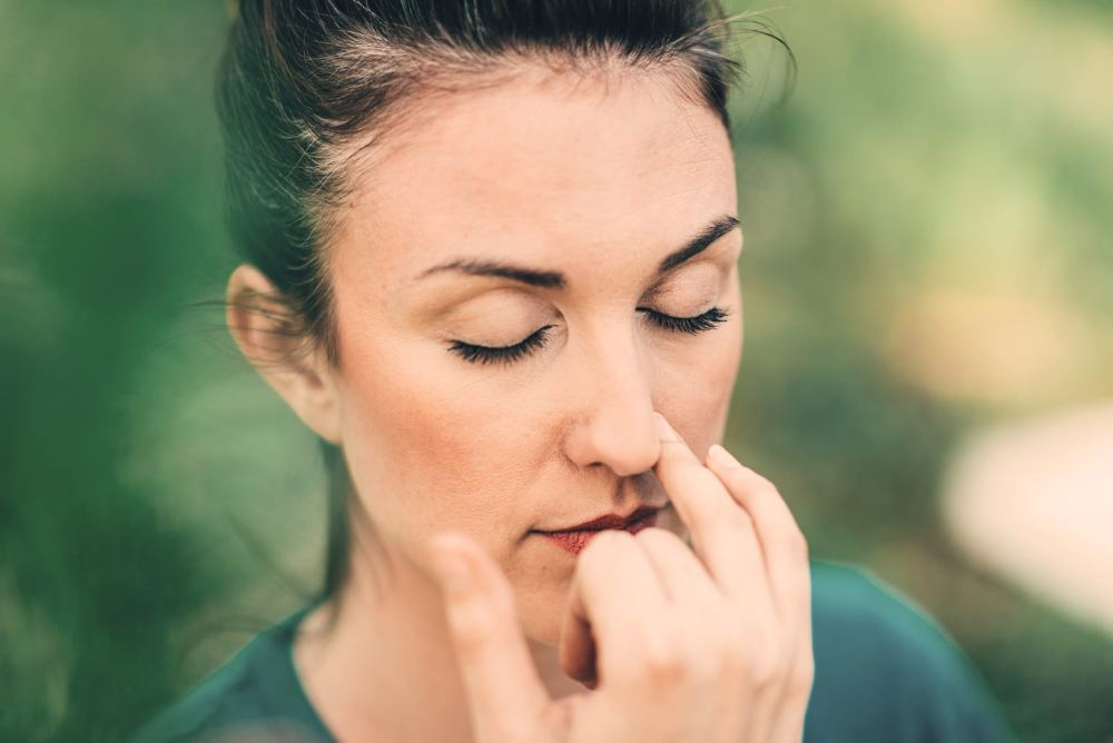 Woman practicing Surya Bhedana Pranayama with eyes closed, closing one nostril with her fingers Woman practicing Surya Bhedana Pranayama with eyes closed, closing one nostril with her fingers