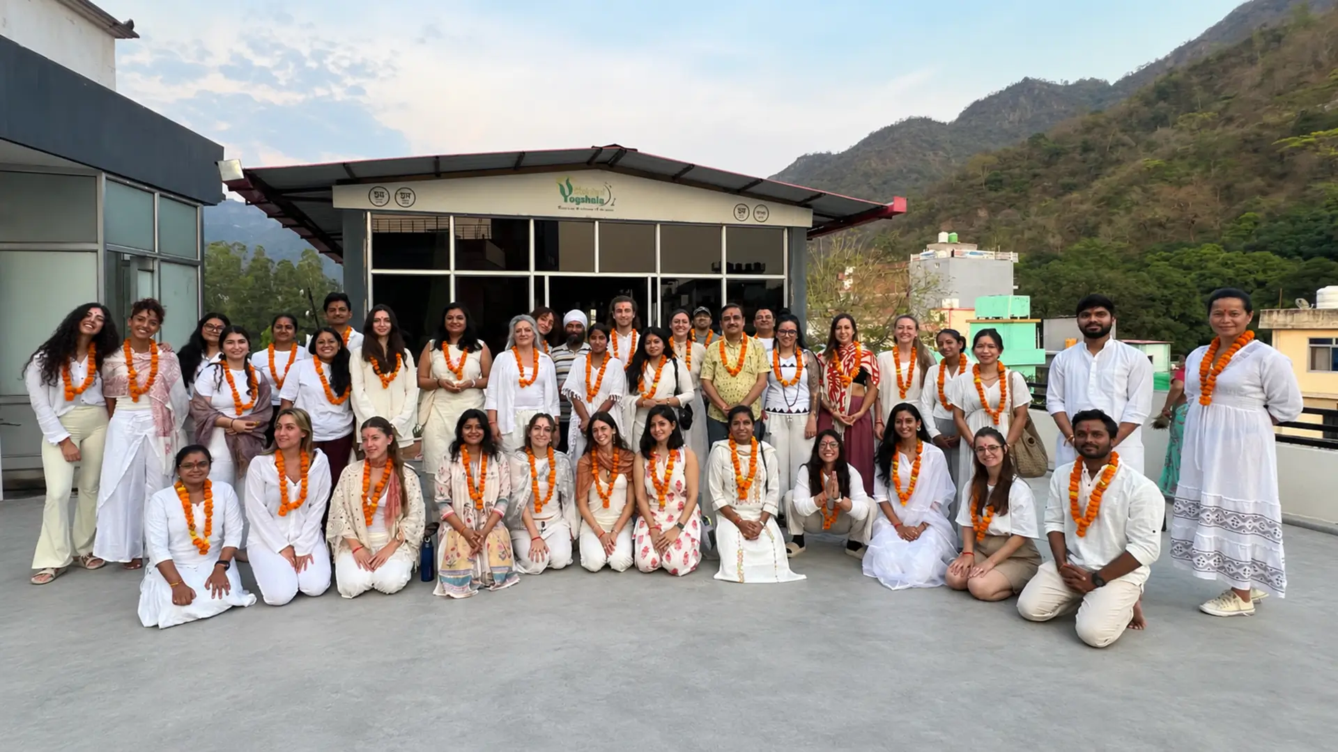 Graduating yoga teacher training batch wearing marigold garlands at Rishikul Yogshala Rishikesh